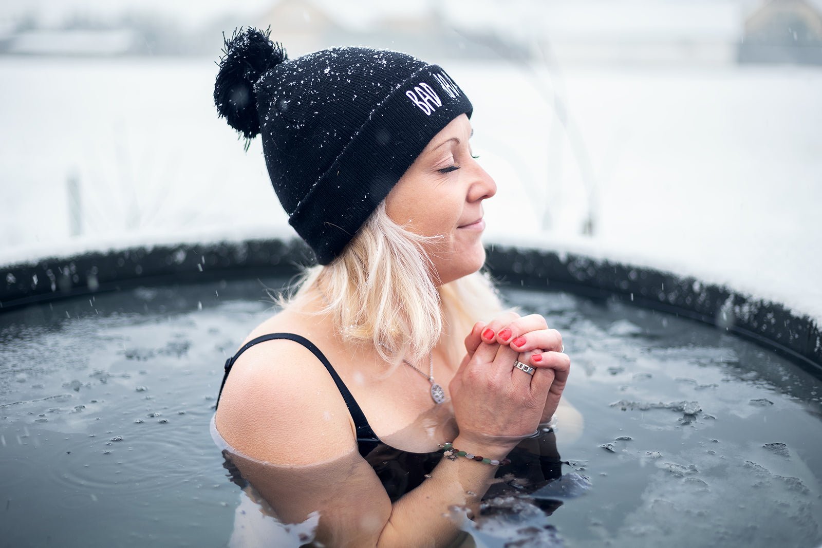 Vrouw zittend in een ijsbad, omringd door koud water, met een serene uitdrukking terwijl ze de kou trotseert.